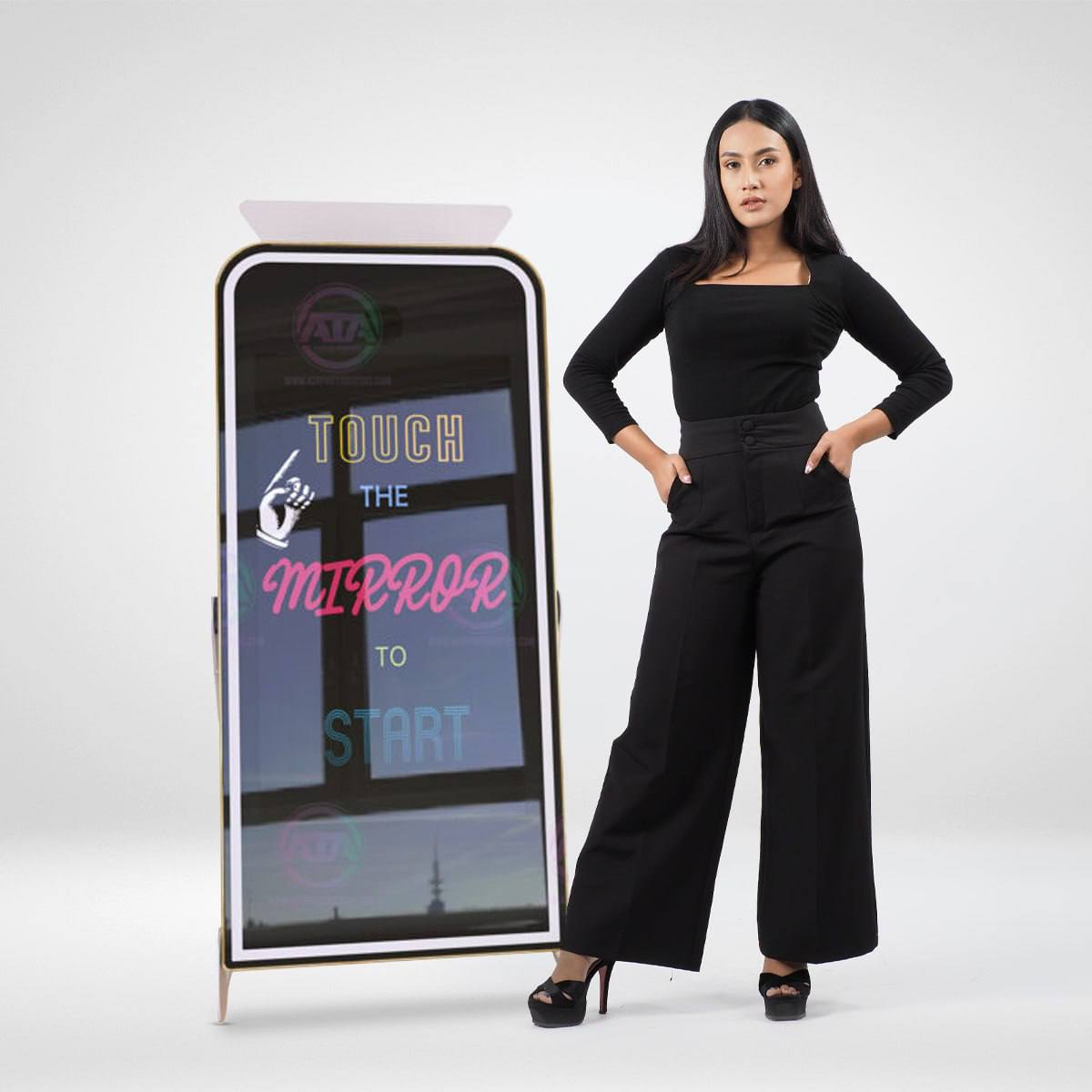 A woman standing next to a mirror photo booth
